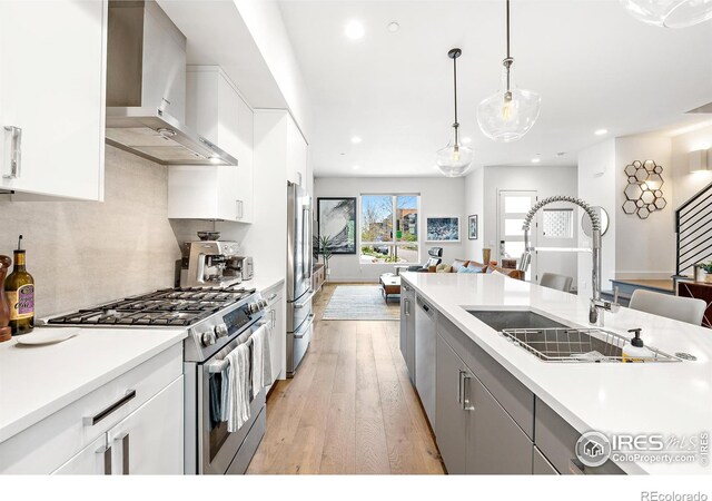 2907 32nd St, Boulder, CO 80301 - kitchen with wall chimney exhaust hood, stainless steel appliances, a sink, open floor plan, and light wood-style flooring