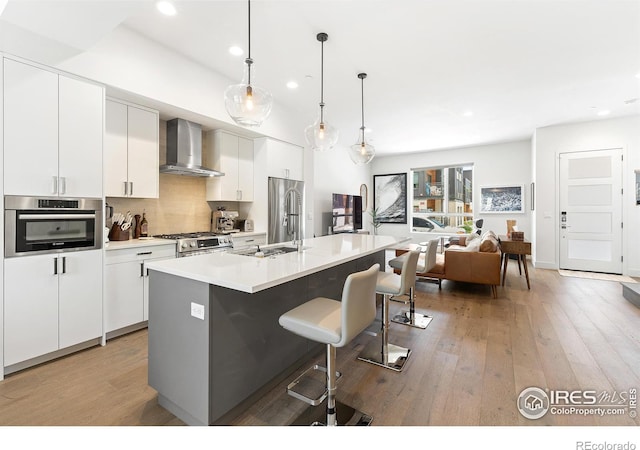 2907 32nd St, Boulder, CO 80301 - kitchen featuring wall chimney range hood, appliances with stainless steel finishes, recessed lighting, light wood-type flooring, and white cabinets