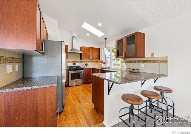 3812 Howe Ct, Boulder, CO 80301 - kitchen featuring stainless steel appliances, wall chimney range hood, brown cabinetry, a peninsula, and light wood-style flooring
