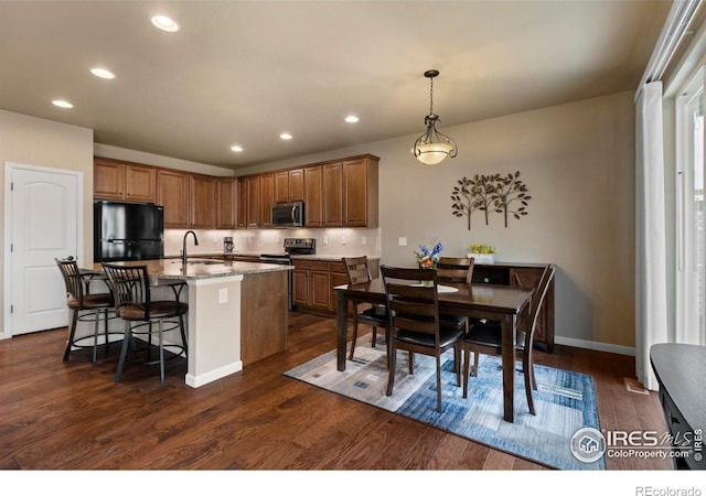 850 Prairiestar Dr, Berthoud, CO 80513 - kitchen featuring brown cabinetry, an island with sink, stainless steel appliances, recessed lighting, and dark wood-type flooring