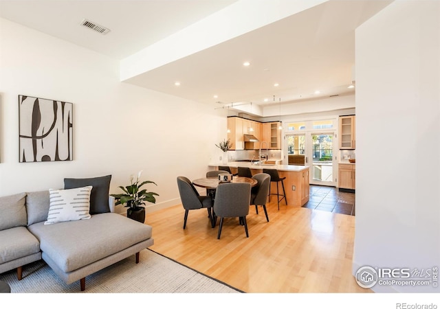 living room featuring recessed lighting, baseboards, light wood-type flooring, and visible vents