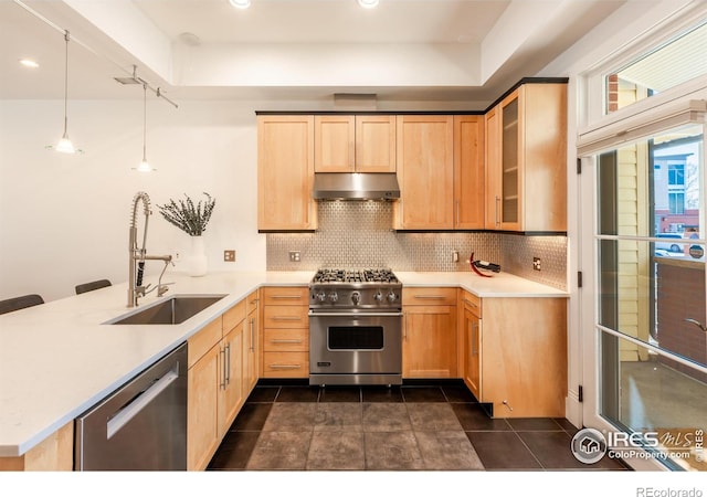 kitchen with a peninsula, light brown cabinetry, under cabinet range hood, a sink, and stainless steel appliances