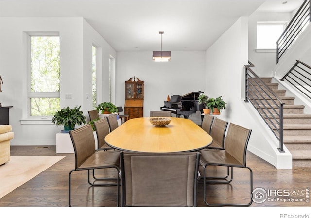 dining area featuring dark wood finished floors, baseboards, a healthy amount of sunlight, and stairs