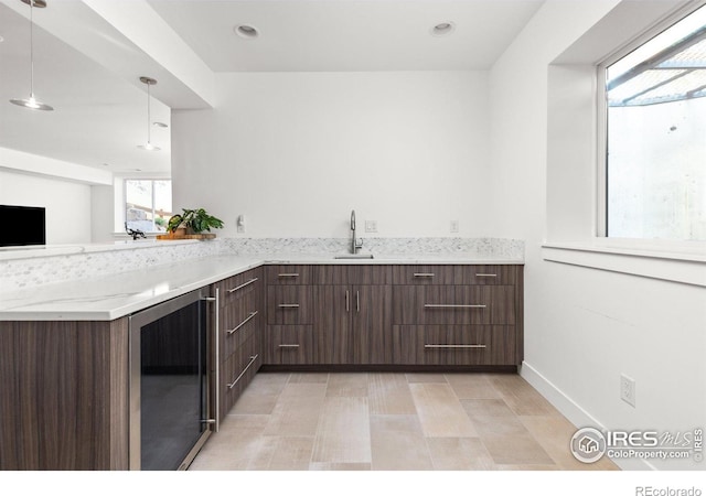 kitchen featuring pendant lighting, beverage cooler, dark brown cabinets, modern cabinets, and a peninsula