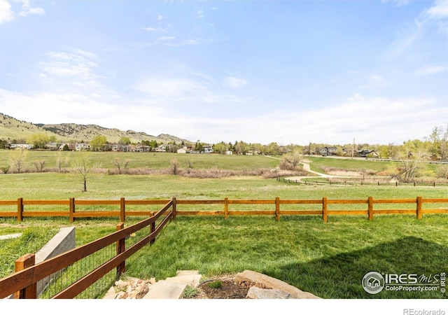 view of yard with a rural view, a mountain view, and fence
