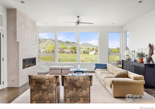 living area with recessed lighting, a mountain view, ceiling fan, wood finished floors, and a tile fireplace