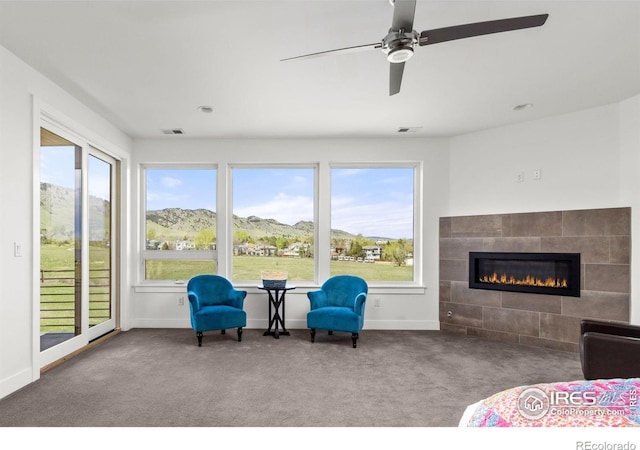 interior space with a mountain view, a fireplace, carpet flooring, a ceiling fan, and baseboards
