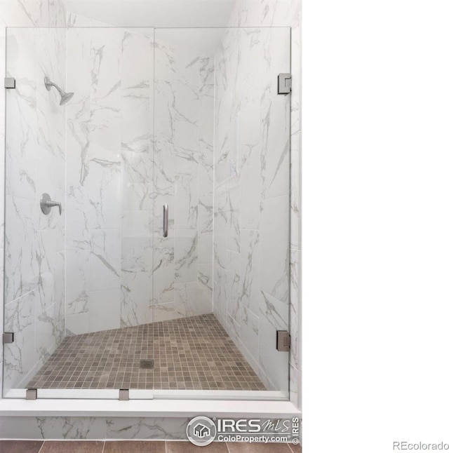 bathroom featuring a marble finish shower