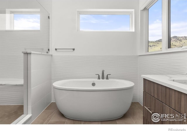 full bath with a soaking tub, tile walls, tile patterned flooring, and walk in shower