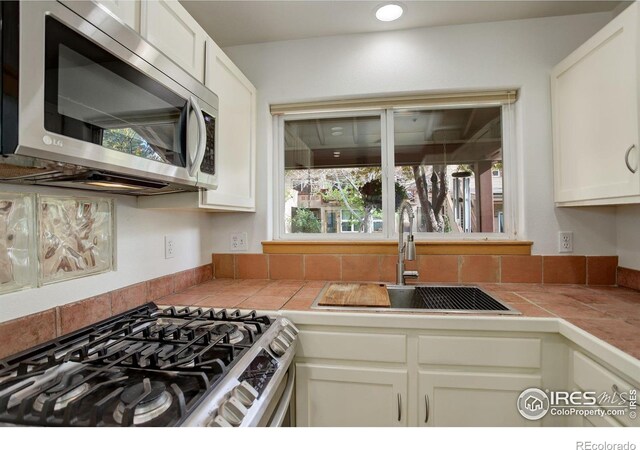 1460 Quince Ave Unit S102, Boulder, CO 80304 - kitchen with stainless steel appliances, a sink, tile countertops, and white cabinetry