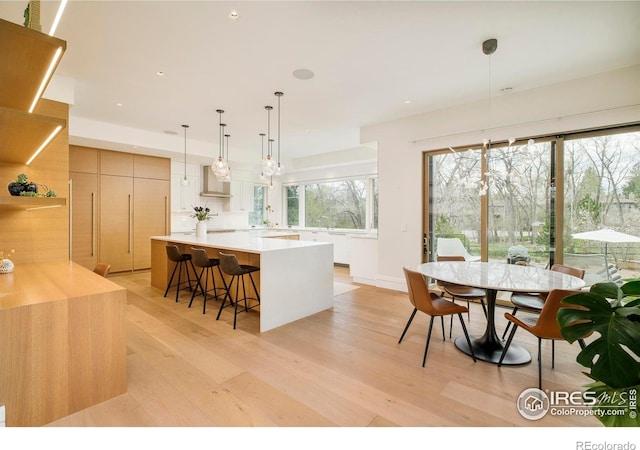2158 Tamarack Ave, Boulder, CO 80304 - kitchen with wall chimney range hood, modern cabinets, a spacious island, light countertops, and light wood-style floors