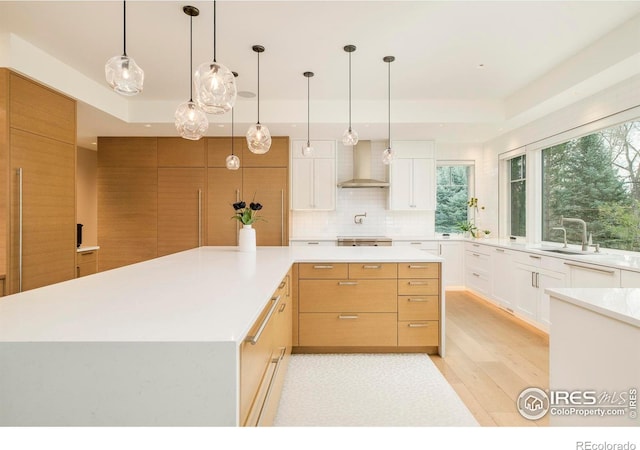 2158 Tamarack Ave, Boulder, CO 80304 - kitchen with wall chimney range hood, a spacious island, light countertops, a sink, and light wood finished floors