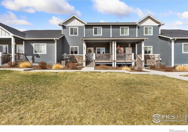 4355 24th Street Rd Unit 202, Greeley, CO 80634 - view of front of home with board and batten siding, covered porch, stone siding, and a front lawn