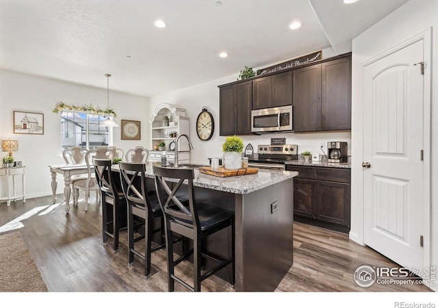 4355 24th Street Rd Unit 202, Greeley, CO 80634 - kitchen with a kitchen island with sink, dark brown cabinetry, appliances with stainless steel finishes, and dark wood-style floors