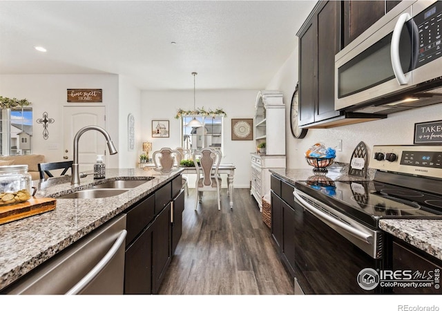 4355 24th Street Rd Unit 202, Greeley, CO 80634 - kitchen featuring dark brown cabinetry, dark wood-style flooring, a sink, light stone counters, and stainless steel appliances
