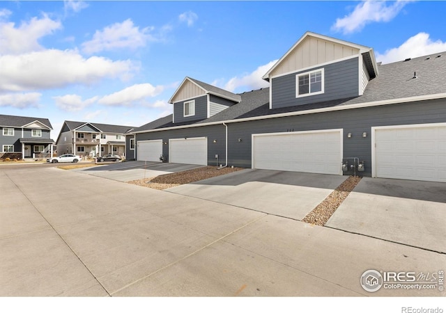 4355 24th Street Rd Unit 202, Greeley, CO 80634 - view of property featuring board and batten siding, driveway, roof with shingles, a residential view, and a garage