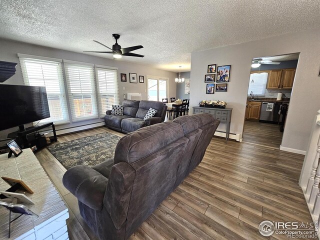 1628 Pheasant Rdg, Sterling, CO 80751 - living room featuring a textured ceiling, dark wood-style floors, baseboard heating, and ceiling fan with notable chandelier