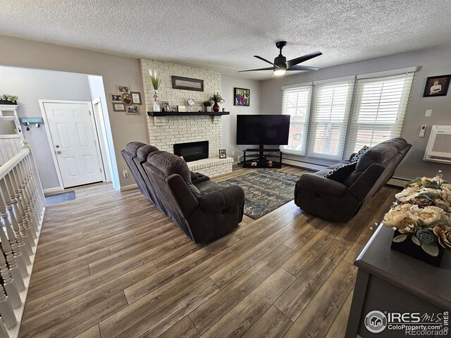 1628 Pheasant Rdg, Sterling, CO 80751 - living area featuring a textured ceiling, ceiling fan, a brick fireplace, and wood finished floors