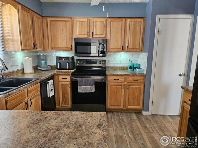 1628 Pheasant Rdg, Sterling, CO 80751 - kitchen with light wood-style floors, a sink, black appliances, and tasteful backsplash