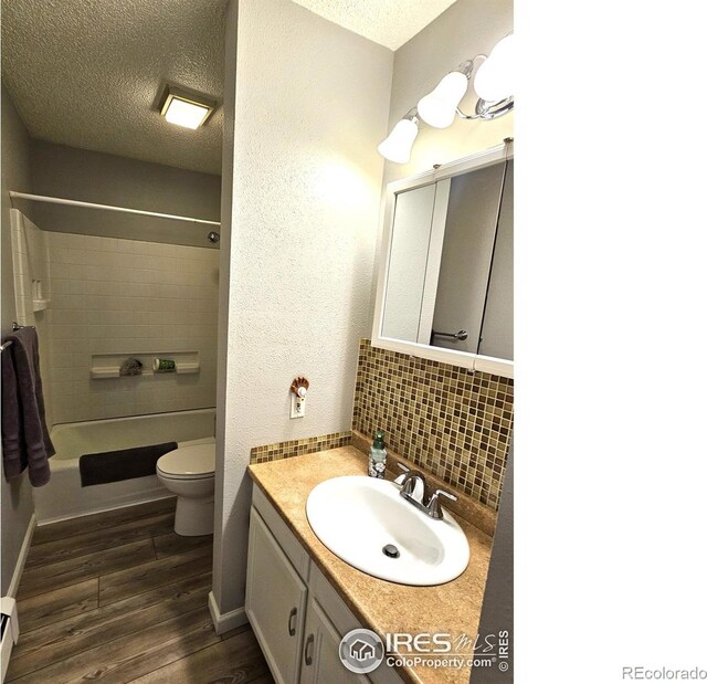 1628 Pheasant Rdg, Sterling, CO 80751 - bathroom featuring vanity, wood finished floors, toilet, a textured ceiling, and tasteful backsplash