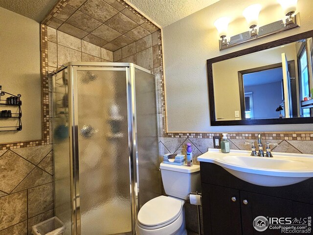 1628 Pheasant Rdg, Sterling, CO 80751 - bathroom featuring tile walls, a stall shower, vanity, a wainscoted wall, and toilet