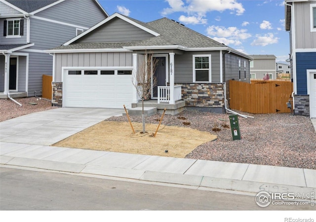 6500 13th St, Frederick, CO 80530 - view of front facade featuring stone siding, roof with shingles, board and batten siding, an attached garage, and concrete driveway