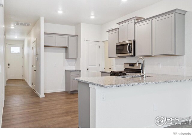 6500 13th St, Frederick, CO 80530 - kitchen featuring appliances with stainless steel finishes, gray cabinetry, light wood-style flooring, a sink, and a peninsula