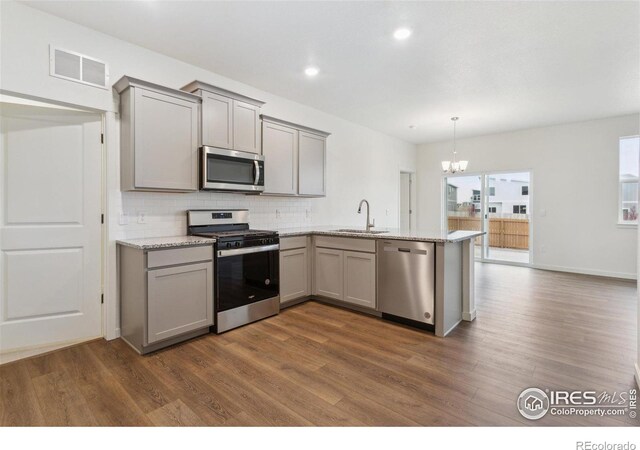 6500 13th St, Frederick, CO 80530 - kitchen with appliances with stainless steel finishes, gray cabinetry, a sink, backsplash, and a chandelier