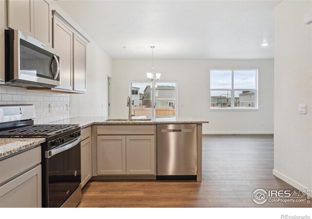 6500 13th St, Frederick, CO 80530 - kitchen featuring appliances with stainless steel finishes, a sink, a peninsula, wood finished floors, and tasteful backsplash