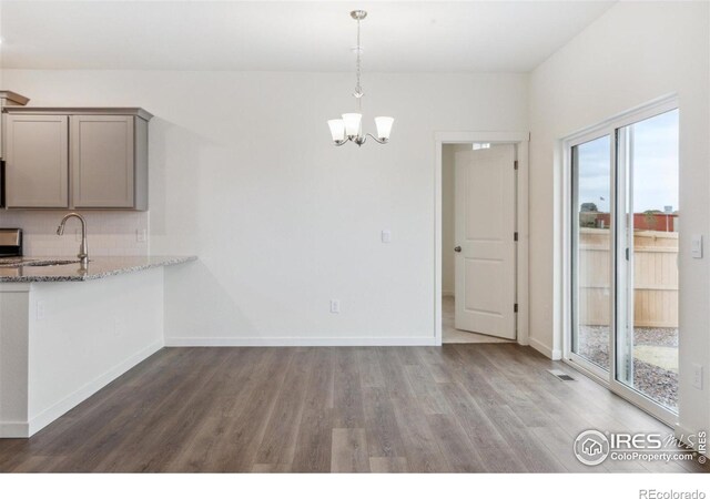 6500 13th St, Frederick, CO 80530 - unfurnished dining area with wood finished floors, a sink, a chandelier, and baseboards