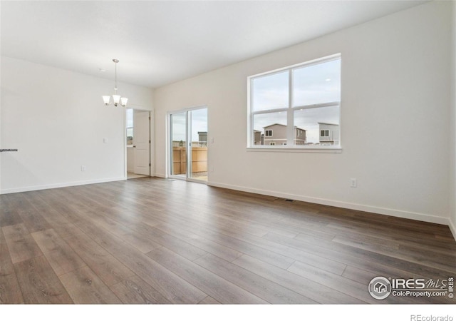 6500 13th St, Frederick, CO 80530 - unfurnished living room featuring a chandelier, wood finished floors, and baseboards