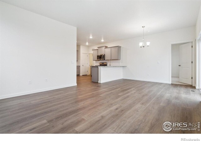 6500 13th St, Frederick, CO 80530 - unfurnished living room featuring a chandelier, light wood-style flooring, and baseboards