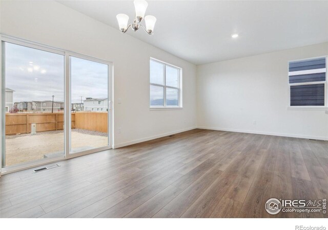 6500 13th St, Frederick, CO 80530 - spare room with wood finished floors, a chandelier, and baseboards