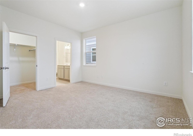 6500 13th St, Frederick, CO 80530 - unfurnished bedroom featuring light carpet, a spacious closet, baseboards, connected bathroom, and a closet