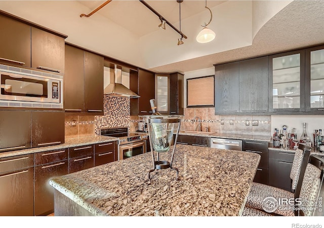 210 W Magnolia St Unit 320, Fort Collins, CO 80521 - kitchen with decorative backsplash, wall chimney exhaust hood, rail lighting, a sink, and appliances with stainless steel finishes