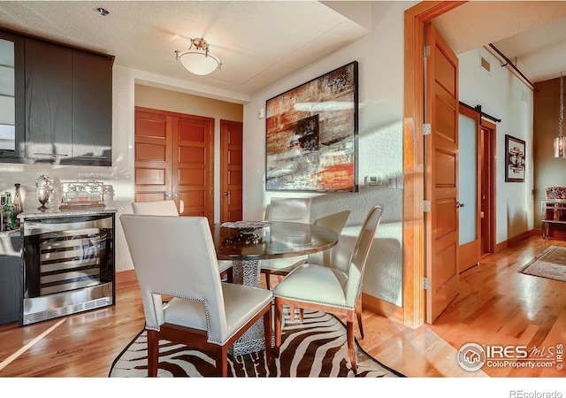 210 W Magnolia St Unit 320, Fort Collins, CO 80521 - dining area featuring visible vents, a barn door, light wood finished floors, and wine cooler