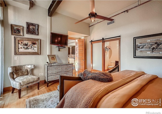 210 W Magnolia St Unit 320, Fort Collins, CO 80521 - bedroom with baseboards, a barn door, beam ceiling, and light wood-type flooring