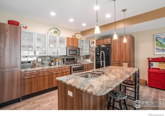 156 Brass Ct Unit 156, Loveland, CO 80537 - kitchen featuring a breakfast bar, stainless steel appliances, brown cabinetry, light wood-style floors, and tasteful backsplash