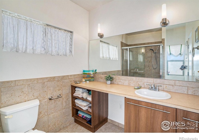 156 Brass Ct Unit 156, Loveland, CO 80537 - bathroom with toilet, a stall shower, a wainscoted wall, tile walls, and vanity