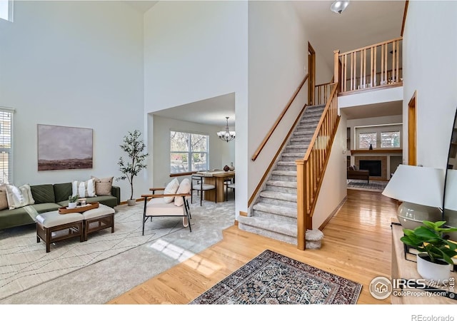 1602 Prairie Song Pl, Longmont, CO 80504 - living area featuring a towering ceiling, a fireplace, a chandelier, light wood-type flooring, and stairway