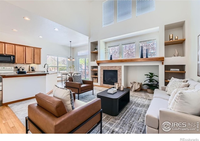 1602 Prairie Song Pl, Longmont, CO 80504 - living area with a high ceiling, a fireplace, light wood-style floors, built in features, and recessed lighting