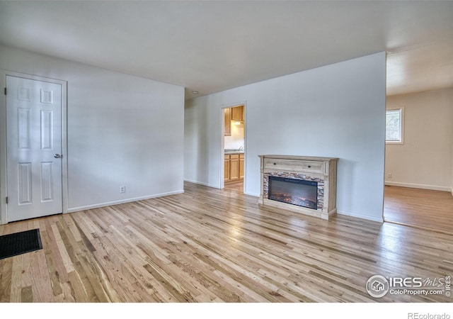810 34th St, Boulder, CO 80303 - unfurnished living room featuring light wood-type flooring, baseboards, and a stone fireplace