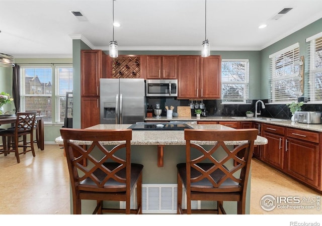 12820 King St, Broomfield, CO 80020 - kitchen with stainless steel appliances, a sink, crown molding, a center island, and hanging light fixtures