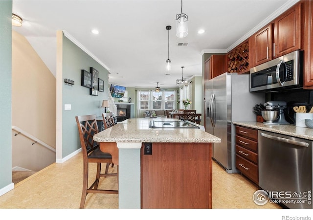 12820 King St, Broomfield, CO 80020 - kitchen with appliances with stainless steel finishes, a kitchen island, crown molding, decorative light fixtures, and open floor plan