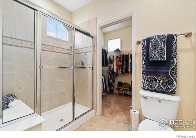 12820 King St, Broomfield, CO 80020 - bathroom with a stall shower, a walk in closet, tile patterned floors, and toilet