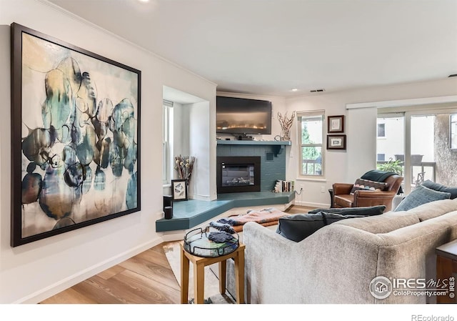 4475 Laguna Pl Unit 206, Boulder, CO 80303 - living room featuring wood finished floors, plenty of natural light, a glass covered fireplace, crown molding, and baseboards