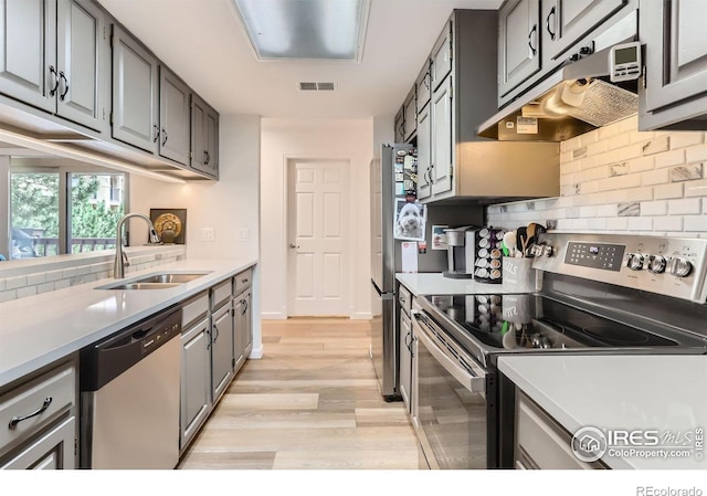 4475 Laguna Pl Unit 206, Boulder, CO 80303 - kitchen featuring stainless steel appliances, a sink, under cabinet range hood, decorative backsplash, and light wood-type flooring