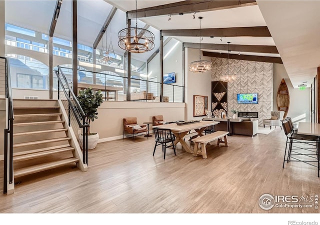 4475 Laguna Pl Unit 206, Boulder, CO 80303 - dining area featuring a chandelier, light wood-style flooring, baseboards, beamed ceiling, and a tiled fireplace