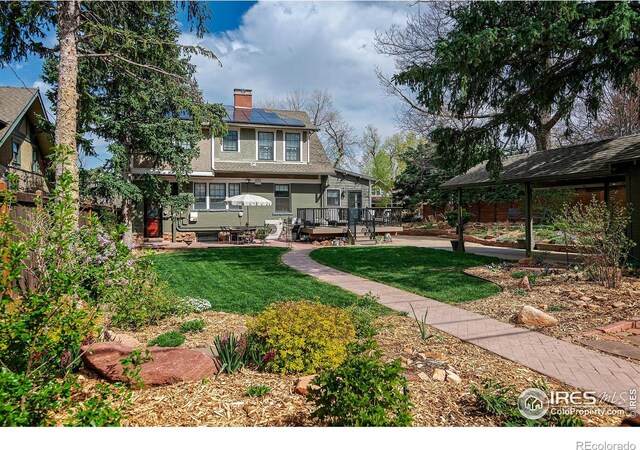 845 14th St, Boulder, CO 80302 - rear view of property with a chimney, roof mounted solar panels, a yard, and a deck