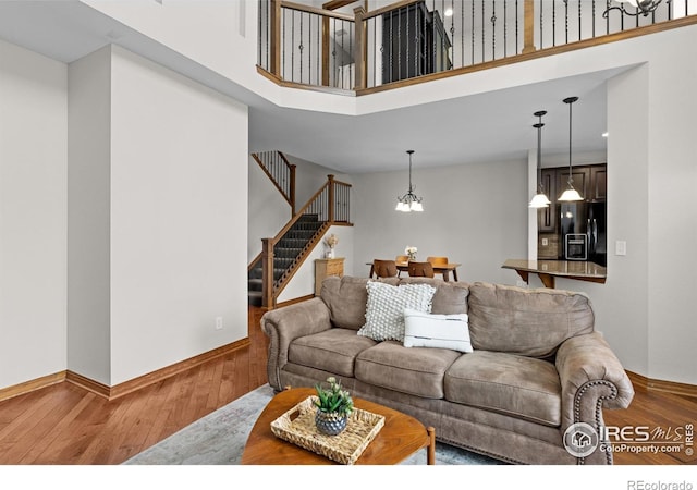 4822 Raven Run, Broomfield, CO 80023 - living room featuring stairs, baseboards, a high ceiling, hardwood / wood-style flooring, and a notable chandelier
